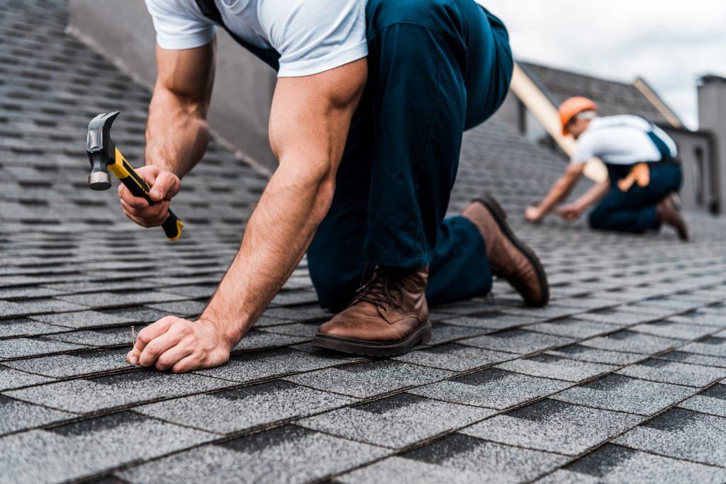 Roofer installing shingles on a residential roof in daylight