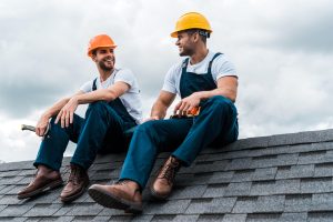 Roofer checking asphalt shingles on a pitched roof